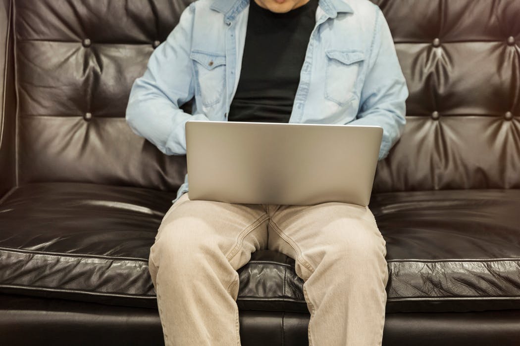 man sitting in a leather lounge while using his laptop